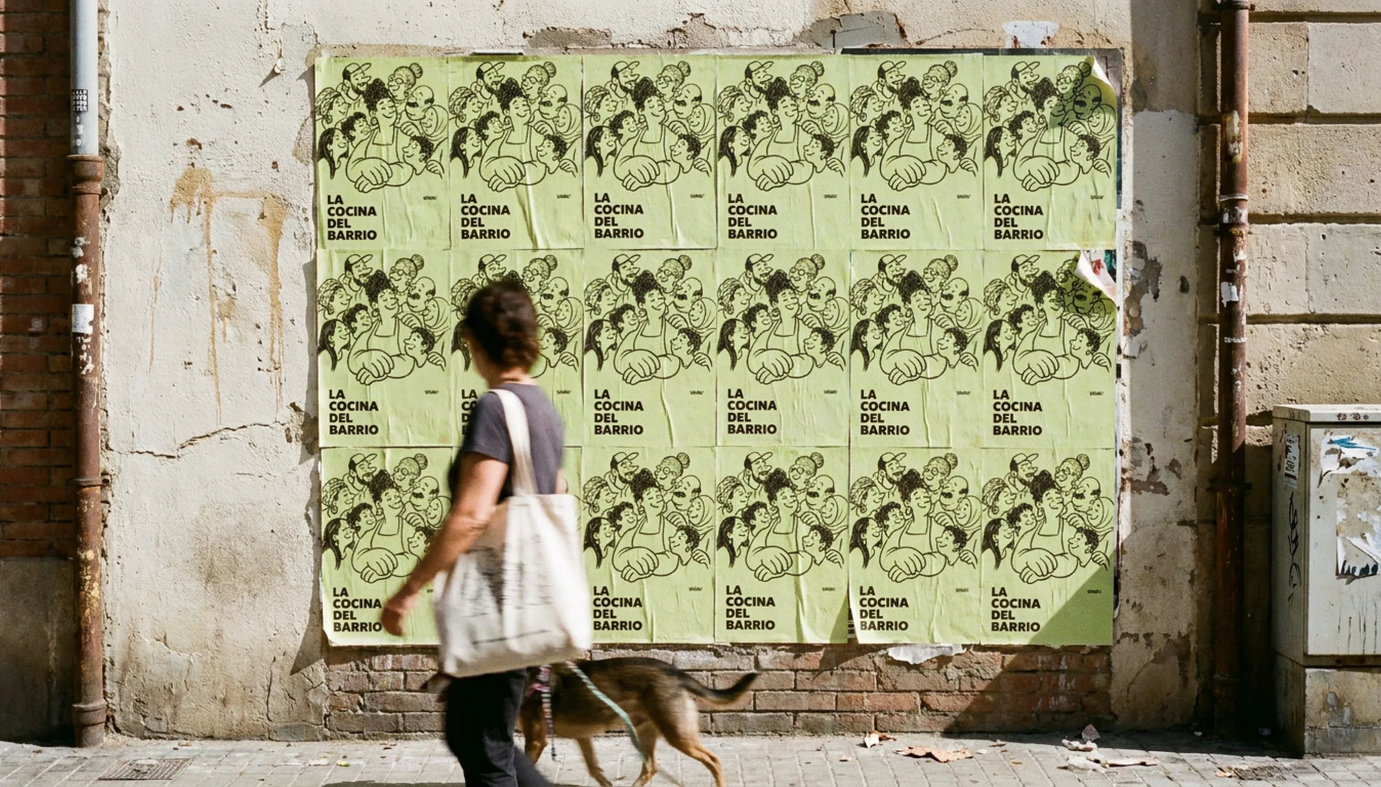 A wall in El Raval fly-posted with tiled lima LA COCINA DEL BARRIO posters
